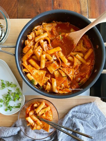 korean tteokbokki served in a pan with serving spoon and bowls on table