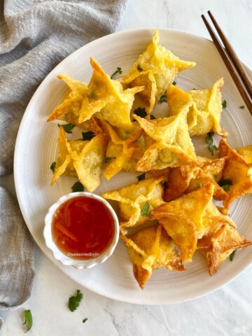 crab rangoon arranged on a plate with sauce