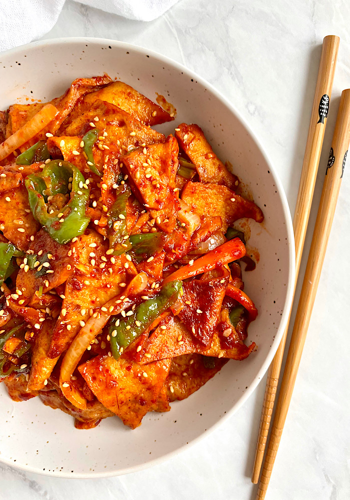 Spicy fish cake stir fry served in a bowl with chopsticks. 