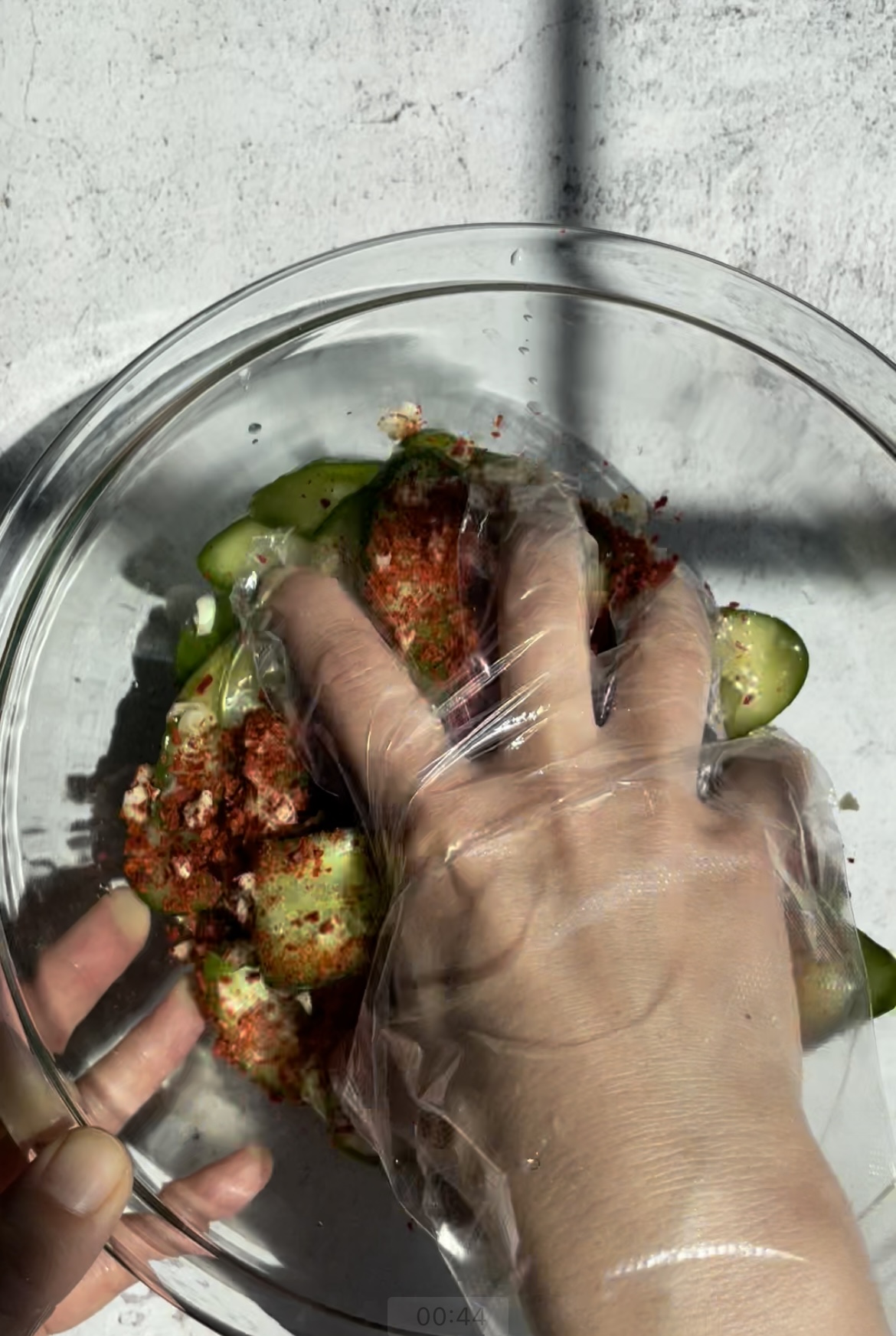 hand tossing cucumbers with gochugaru