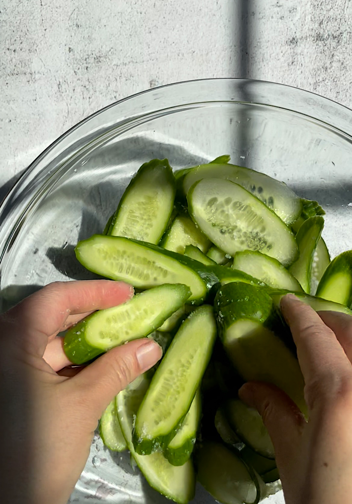 tossing salt onto cucumbers